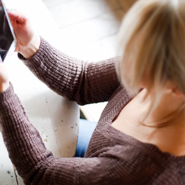 Woman sitting at a desk, thoughtfully brainstorming money-making ideas.